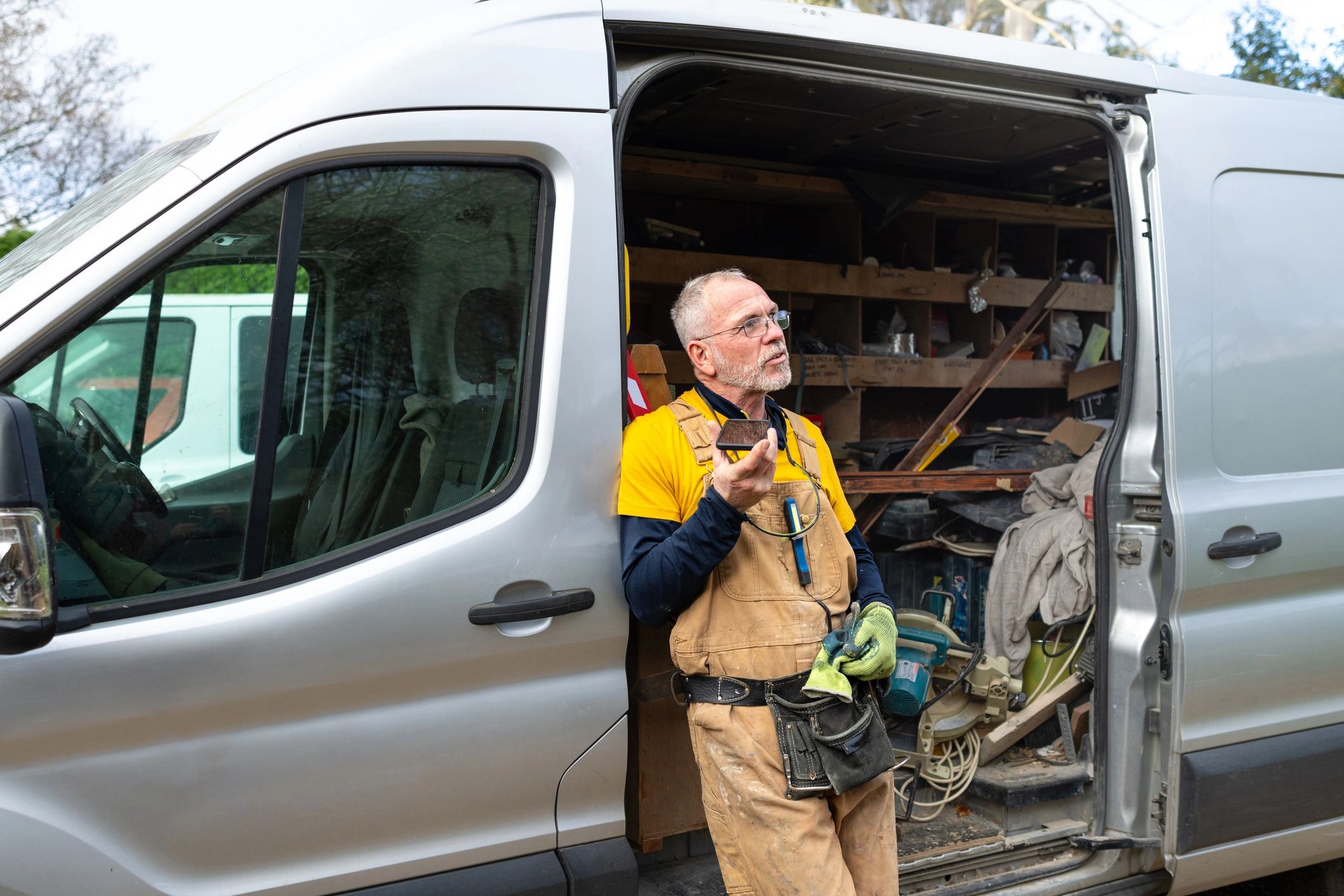 RV repair technician standing by service van and talking on his phone
